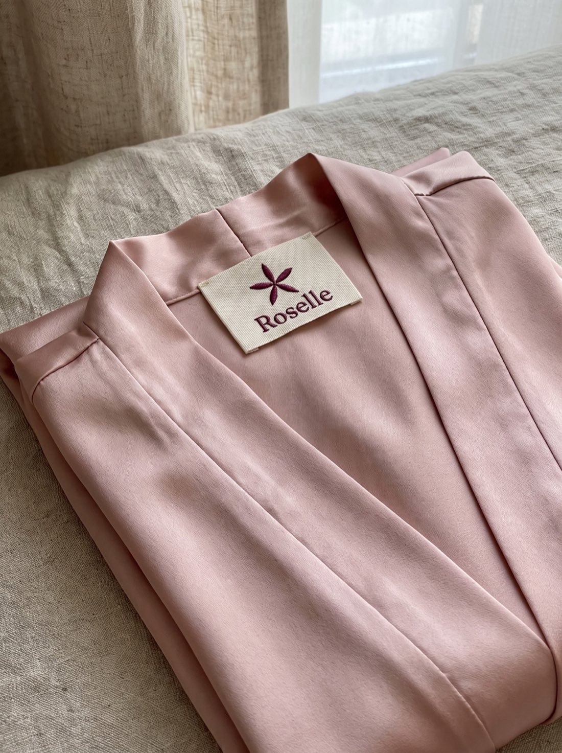 Embroidered Roselle garment label on blush satin